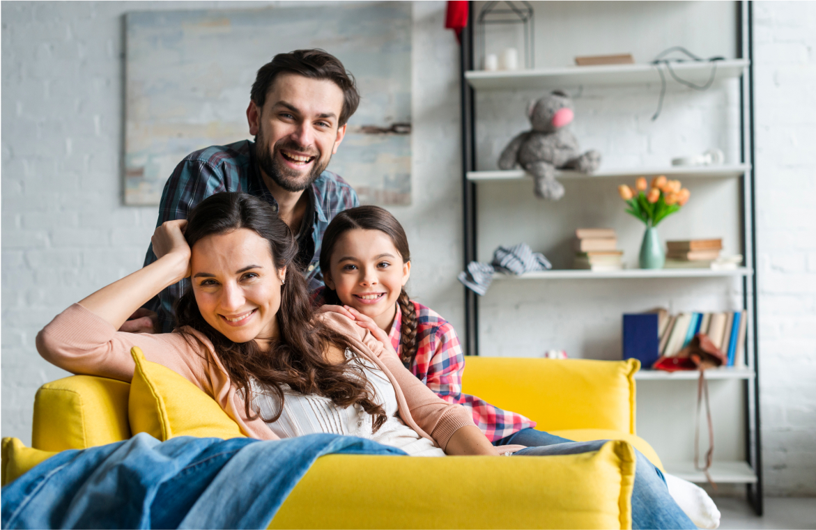 familia sonriendo hacia la cámara sentados sobre un sillón amarillo