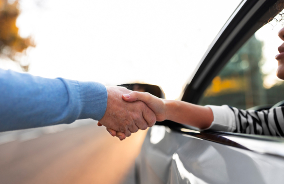 persona dándole la mano a alguien dentro de un auto